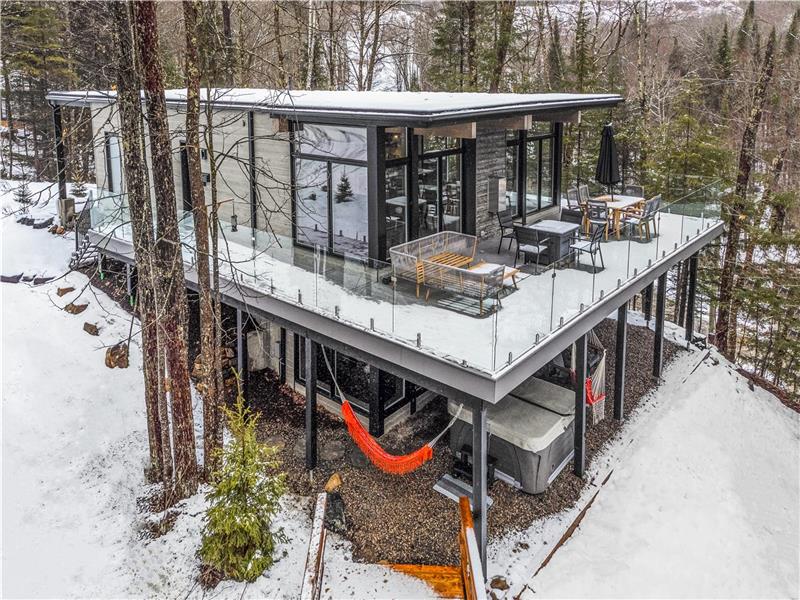 Chalet Oracle vu depuis le ciel — terrasse vitrée suspendue au cœur de la forêt enneigée des Laurentides